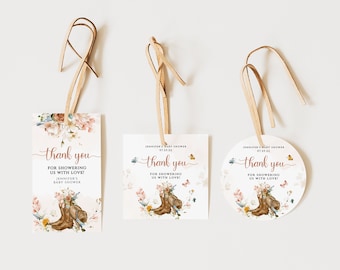 May include: Three thank you tags for a baby shower. The tags are decorated with floral designs, butterflies, and a pair of cowboy boots. The text on the tags reads "Thank you for showering us with love!"