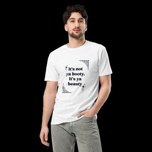 Può includere: T-shirt bianca con una grafica nera che dice "It's not ya booty, It's ya beauty" con un bordo decorativo.
