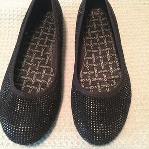 May include: A pair of black sparkly flats with a Vionic logo on the insole.