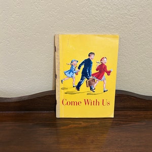 May include: A yellow book with a picture of three children walking. The book title is "Come With Us".