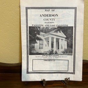 May include: Black and white map of Anderson County, Texas, featuring Palestine and Lake Palestine. The map includes a photo of the Howard House Museum, which was built in 1901 and has a Texas Historical Survey Medallion. The text "Compliments of" is at the bottom of the map.