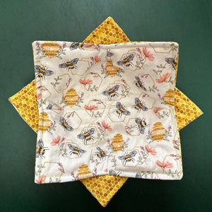 May include: A white fabric bowl with a honeycomb pattern and bee illustrations. The bowl is lined with a yellow fabric with a honeycomb pattern.