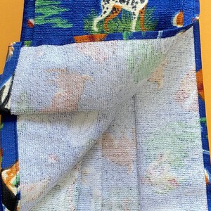 May include: A blue and white kitchen towel with a dog and camping theme. The towel is folded in half and the inside is white.