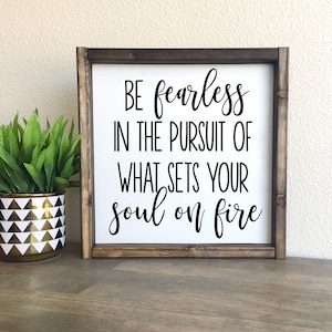 May include: A wooden sign with a white background and black text that reads "Be fearless in the pursuit of what sets your soul on fire".