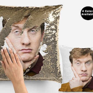May include: A gold sequin pillow with a man's face peeking out from behind the sequins. The man is looking at the camera with a serious expression. The pillow is reversible and has a white side with a different image of the man. The text "4 Colors Available" is visible in the upper right corner of the image.