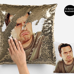 May include: A gold sequin cushion with a picture of a man with a grumpy expression. The cushion is reversible and the other side shows the same picture on a white background. The text "4 Colors Available" is visible in the upper right corner of the image.