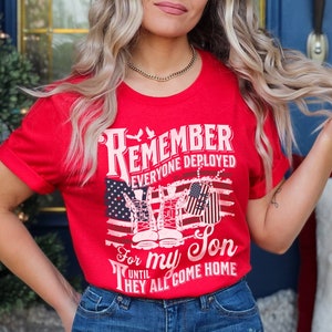 May include: Red t-shirt with a white graphic that says "Remember Everyone Deployed For My Son Until They All Come Home". The graphic also features a pair of boots and dog tags.
