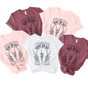 Pu&ograve; includere: Cinque t-shirt di diversi colori con il testo "Ride or Die" e una mano scheletrica con un segno di pace. Una maglietta dice invece "Bride or Die".