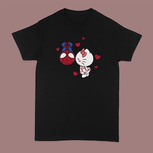 Peut inclure: T-shirt noir avec un imprim&eacute; de Spiderman embrassant Hello Kitty. L'imprim&eacute; est en rouge, blanc et bleu. Il y a de petits c&oelig;urs rouges autour de l'imprim&eacute;.