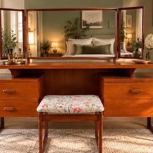 May include: A wooden vanity table featuring a large tri-fold mirror, two sets of stacked drawers with horizontal handles, and a matching stool with a floral patterned seat cushion. The furniture is constructed from a warm-toned wood finish.