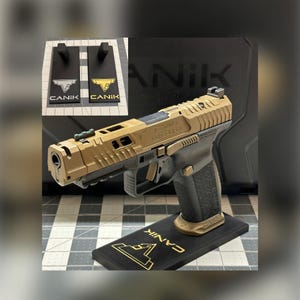 May include: A tan and black semi-automatic pistol with a textured grip, mounted on a black display stand featuring the gold CANiK logo. The slide has cutouts and a green fiber optic front sight. An inset shows two stands with white and gold logos.