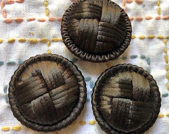 Può includere: Tre bottoni marroni in tessuto intrecciato con un design a griglia rialzato.