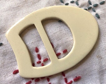 Half oval white carved casein belt slide 1930's