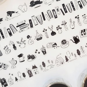 May include: Five rolls of black and white washi tape with different designs. The designs include books, houses, coffee cups, plants, and dogs. The tape is labeled "Shiro to Kuro no Masking Tape" which translates to "White and Black Masking Tape".