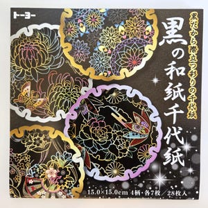 May include: A pack of Japanese washi paper with floral and butterfly patterns. The paper has a black background with gold, purple, and iridescent details. Each sheet measures 15.0 x 15.0 cm.