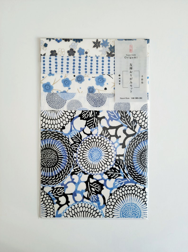 May include: A pack of origami paper featuring a variety of blue and white patterns. The paper is 15cm x 15cm and is made in Japan. The text on the label reads "Yuzen Washi Origami" and "Naguri Gama"