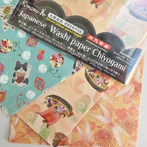 May include: A pack of 24 Japanese Washi paper sheets with a variety of colorful designs. The pack is labeled "Kimono Japanese Washi Paper Chiyogami" and includes the text "Great wish fulfillment. Good luck chiyogami" and "Prosperous business".