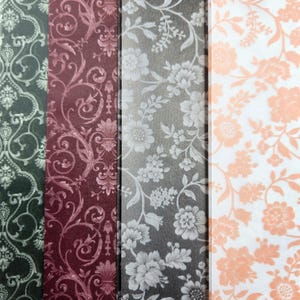 May include: A close-up of four patterned paper samples. The first is dark green with a white scroll design. The second is burgundy with a floral pattern. The third is gray with white flowers. The fourth is white with peach flowers.
