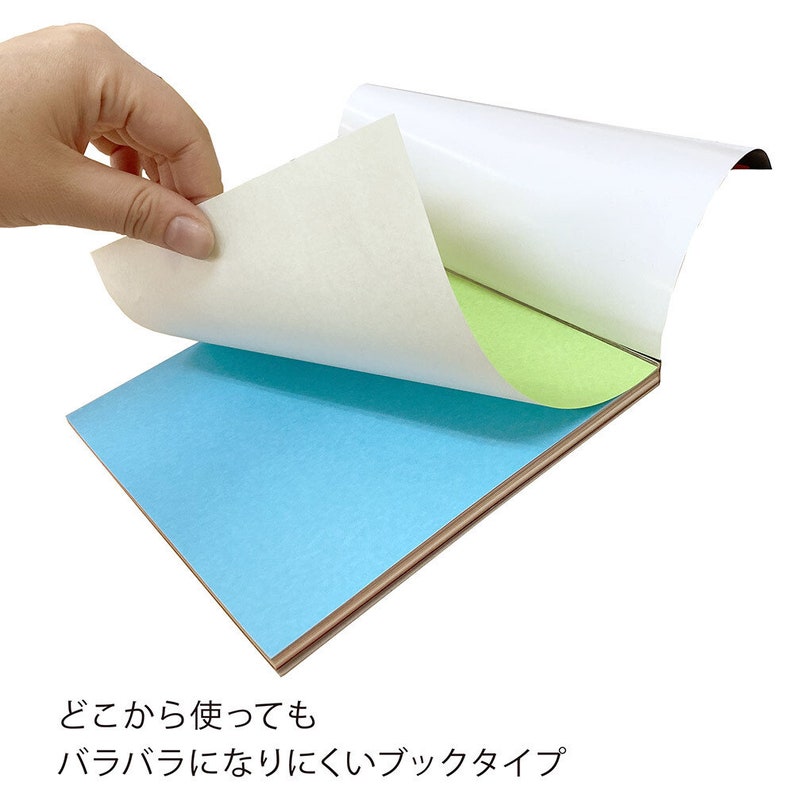 May include: A notepad with blue and green pages, with a white cover being lifted to reveal the pages. The notepad has a wooden-coloured base. Japanese text is visible at the bottom of the image.