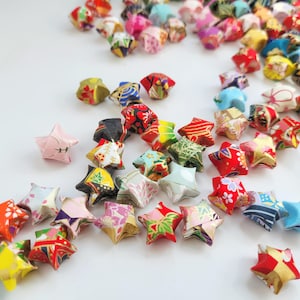 May include: A collection of colourful origami stars, folded from patterned paper. The stars are in various shades of red, blue, green, pink, and yellow.