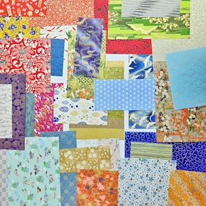 May include: A collection of colorful patterned origami paper sheets. The papers feature various designs, including floral, geometric, and wave patterns, in shades of red, blue, green, and gold. The papers are arranged in a collage-like composition.
