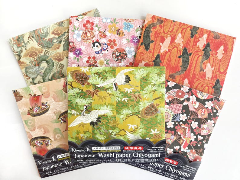 May include: A set of six Japanese washi paper sheets with various traditional designs, including cranes, fish, flowers, and dragons. The paper is gold, red, black, and white. The packaging includes the text "Japanese Washi Paper Chiyogami".