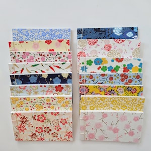 May include: A set of 16 small, colorful notebooks with various floral and geometric patterns. The notebooks are bound with white string and have a Japanese aesthetic.