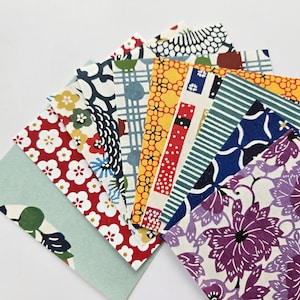 May include: A collection of colorful patterned paper squares with various floral, geometric, and abstract designs. The papers are arranged in a fan shape, showcasing the different patterns.