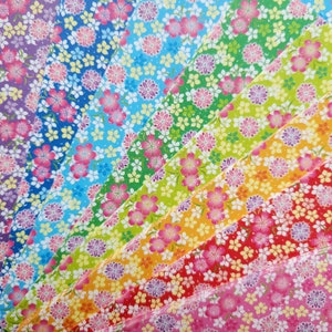 May include: A set of 10 colorful origami paper sheets with a floral pattern. The paper is arranged in a fan shape, with the colors transitioning from purple to pink, red, orange, yellow, green, blue, and light blue.
