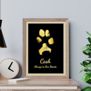 May include: Gold paw print on a black background with the name "Cash" and the text "Always in Our Hearts" in a gold frame.