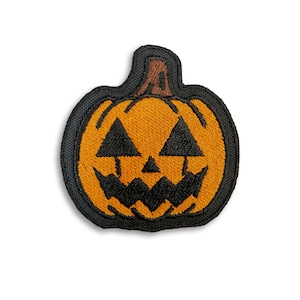 以下が含まれることがあります： 怖い顔をしたジャック・オー・ランタンの黒とオレンジの刺繍パッチ