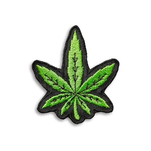 May include: Embroidered patch depicting a green cannabis leaf with intricate stitching. The leaf is set against a black background with a black border, creating a striking contrast. The patch is suitable for clothing or accessories.