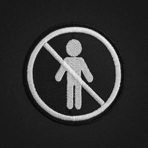 Könnte beinhalten: Ein schwarz-weißer, gestickter Aufnäher mit einem weißen Strichmännchen in einem weiß umrandeten Kreis, der von einer diagonalen Linie durchzogen ist, ein Verbotssymbol. Der Aufnäher ist kreisförmig und vor einem schwarzen Hintergrund platziert.