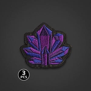 May include: An embroidered patch featuring a cluster of pointed crystals in shades of deep purple, violet, and blue, outlined with black thread. The design is shaped like a jagged formation. A small circular icon in the corner displays the text 3 PCS.