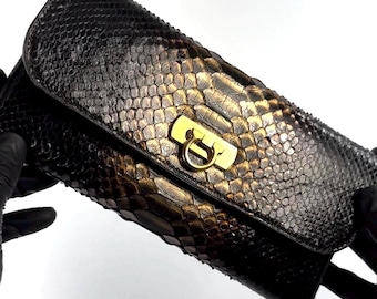 Bolso de mano para mujer de piel de serpiente en color negro y dorado.