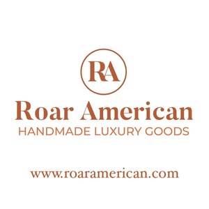May include: Logo for Roar American, a company that makes handmade luxury goods. The logo features a circle with the letters "RA" inside, and the words "Roar American" and "Handmade Luxury Goods" below the circle. The website address, www.roaramerican.com, is displayed below the text.