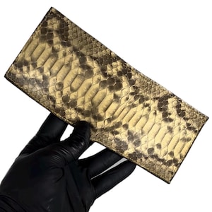Peut inclure: Un portefeuille long et rectangulaire en peau de serpent brun clair avec un motif texturé.