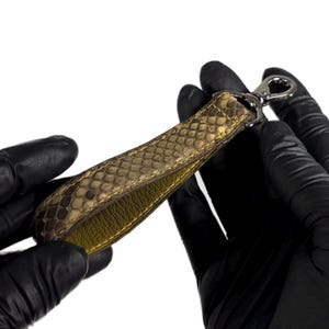 May include: A brown leather key chain with a silver hook. The leather has a snakeskin pattern.