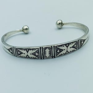 Peut inclure: Un bracelet en argent avec un motif géométrique gravé sur la surface.
