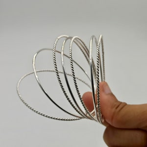 May include: A set of six silver bangles with a twisted rope design.