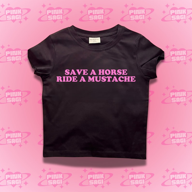 Puede incluir: Camiseta negra con texto rosa que dice "Save a Horse Ride a Mustache".