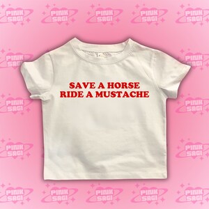 Puede incluir: Camiseta blanca con texto rojo que dice "Salva un caballo, monta un bigote".