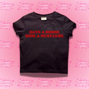 Puede incluir: Camiseta negra con texto rojo que dice "Save a Horse Ride a Mustache".