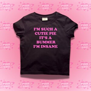 May include: Black t-shirt with pink text that reads "I'm such a cutie pie it's a bummer I'm insane".