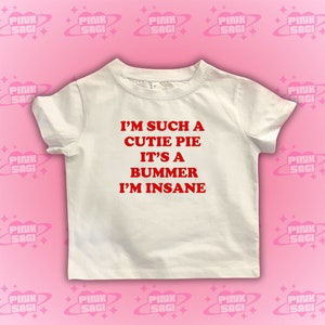 May include: White t-shirt with red text that reads "I'm such a cutie pie it's a bummer I'm insane."