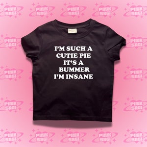 May include: Black t-shirt with white text that reads "I'm such a cutie pie it's a bummer I'm insane."