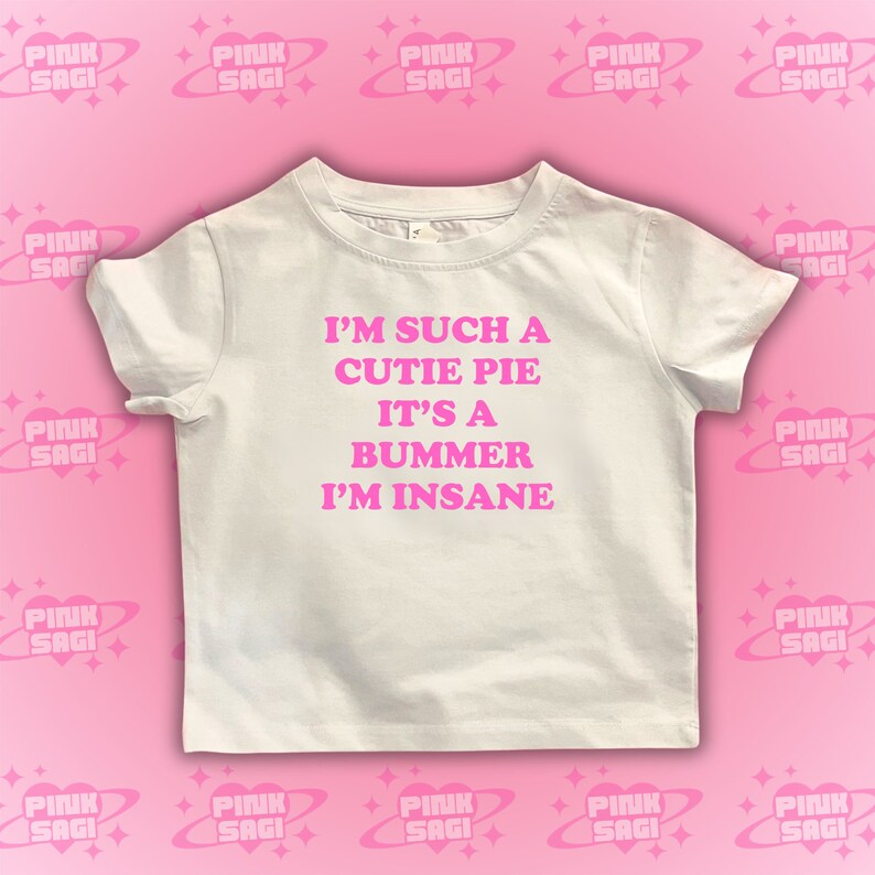 May include: White t-shirt with pink text that reads "I'm such a cutie pie it's a bummer I'm insane."