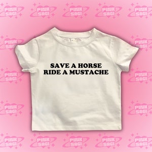 Puede incluir: Camiseta blanca con texto negro que dice "Save a horse, ride a mustache".