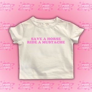 Puede incluir: Camiseta blanca con texto rosa que dice "Save a horse, ride a mustache".