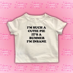 May include: White t-shirt with black text that reads "I'm such a cutie pie it's a bummer I'm insane".
